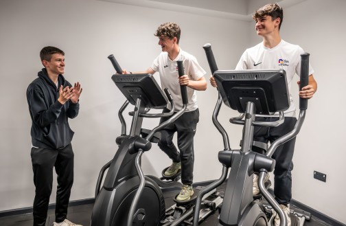 Two sports students using the cross trainers, with another student standing to the side