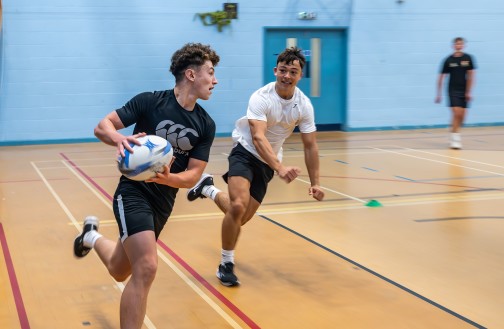 Two students playing rugby in our Sports Hall
